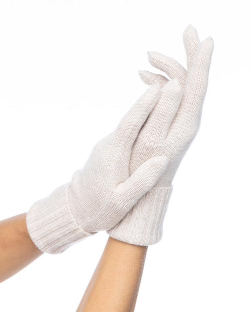 Hands wearing light oatmeal-colored cashmere gloves against a white background