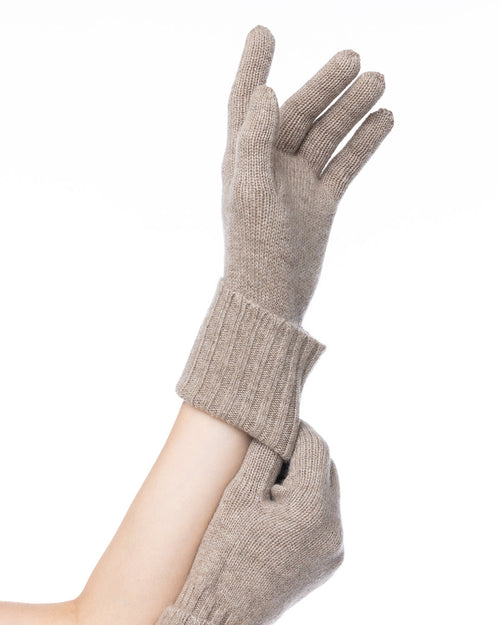 LIFESTYLE / EDITORIAL: Hands wearing beige cashmere gloves against white background
