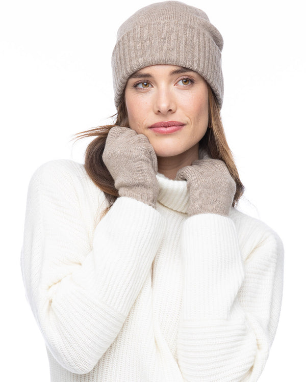 LIFESTYLE / EDITORIAL: Woman wearing beige cashmere hat and gloves with white cashmere sweater against white background