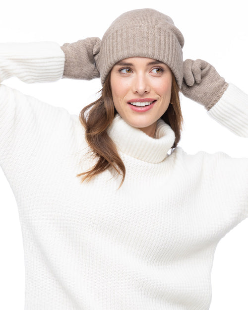 LIFESTYLE / EDITORIAL: Woman wearing beige cashmere hat and gloves with white cashmere turtleneck sweater, smiling