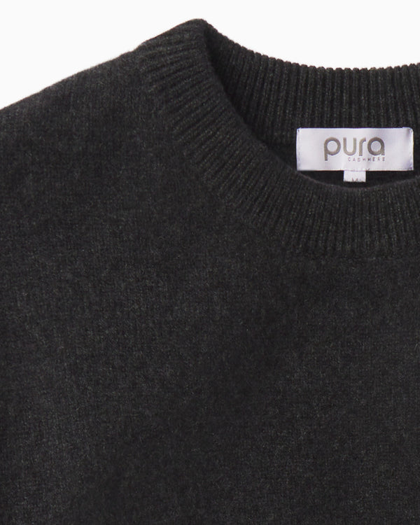Close-up of charcoal-colored cashmere crew neck sweater with ribbed collar and "pura cashmere" label visible