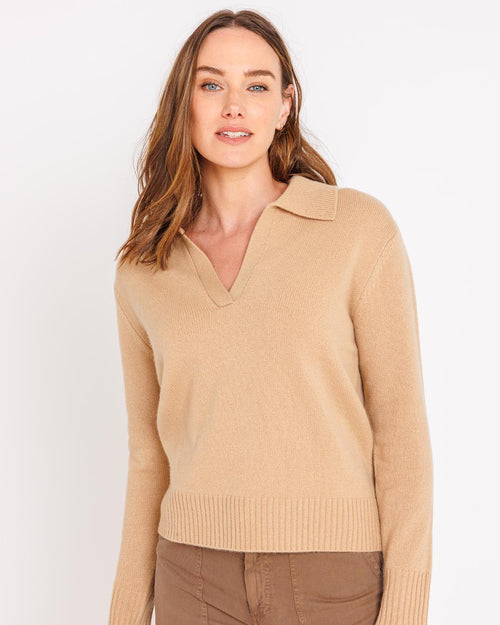 LIFESTYLE / EDITORIAL: Woman wearing camel-colored cashmere polo sweater with collar, standing against white background