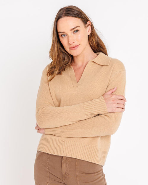 LIFESTYLE / EDITORIAL: Woman wearing camel cashmere polo sweater and brown pants, posing against white background