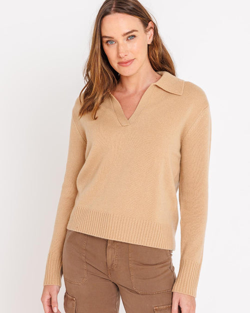 LIFESTYLE / EDITORIAL: Woman wearing camel-colored cashmere polo sweater and brown pants against white background