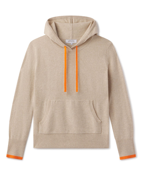 LIFESTYLE / EDITORIAL: Beige cashmere hoodie with orange drawstrings and cuff accents, laid flat on white background