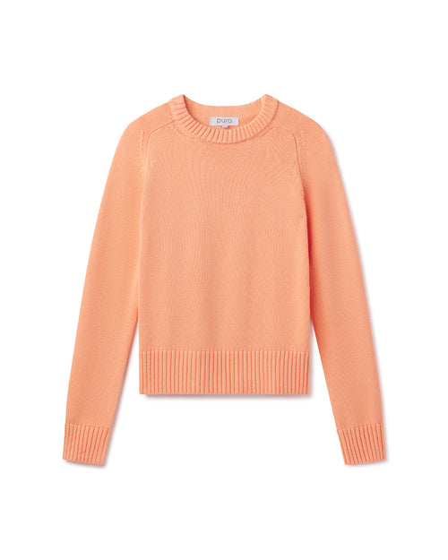 Cashmere crewneck sweater in coral color, long sleeves, ribbed cuffs and hem, flat lay on white background