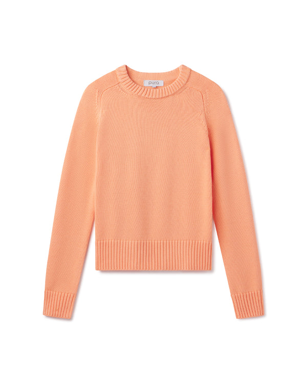 Cashmere crewneck sweater in coral color, long sleeves, ribbed cuffs and hem, flat lay on white background