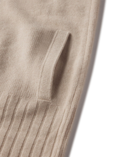 Close-up of oatmeal-colored cashmere zip-up cardigan pocket and ribbed hem texture