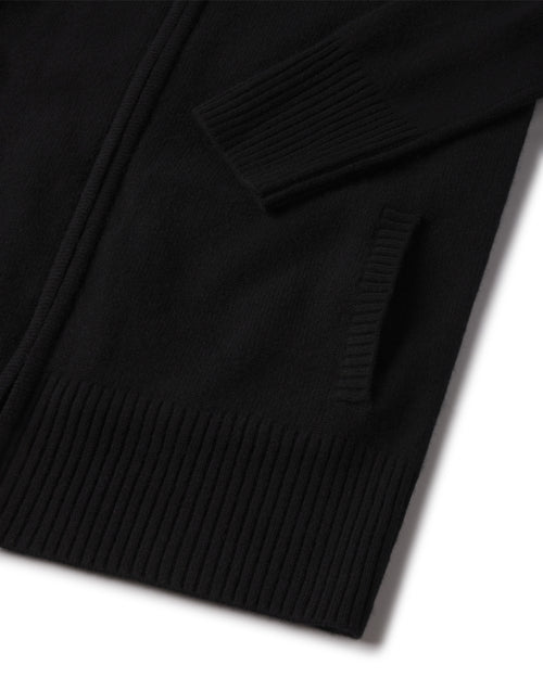 Close-up of black cashmere cardigan sleeve, pocket, and ribbed hem detail
