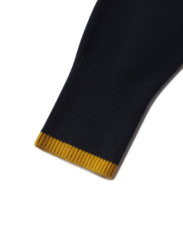 Detail image of a navy cashmere hoodie sleeve with gold ribbed cuff trim on a luxury garment