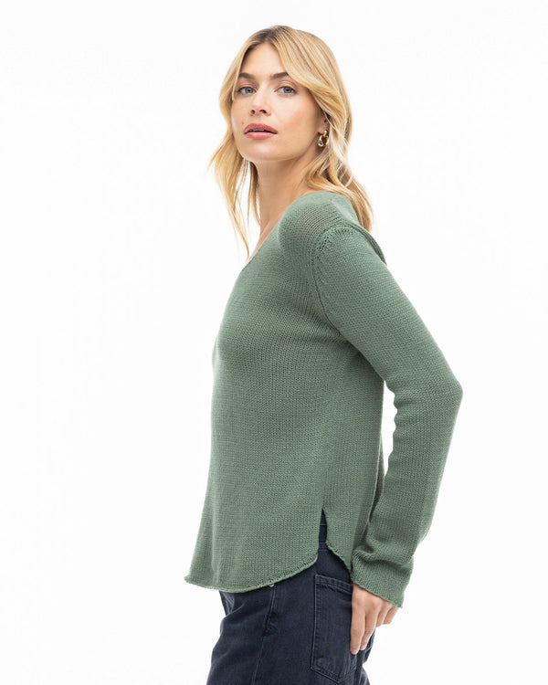 LIFESTYLE / EDITORIAL: Woman in olive green cashmere sweater, side view, against white background