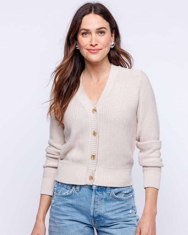 LIFESTYLE / EDITORIAL: Woman wearing oatmeal-colored textured cardigan and blue jeans against white background