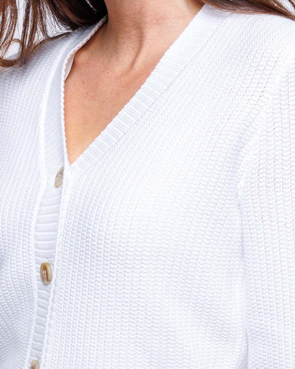 Close-up of white textured knit cardigan with buttons on a woman's upper torso