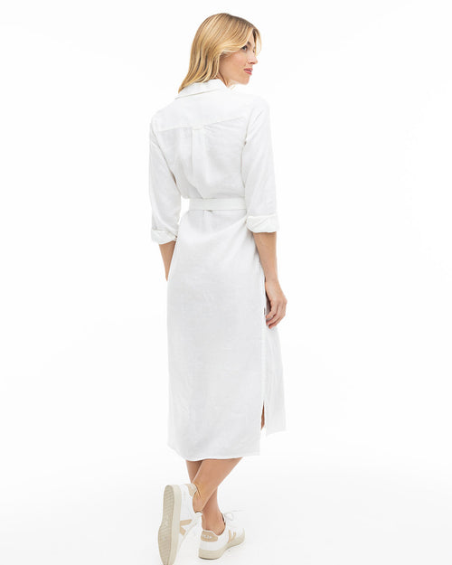 LIFESTYLE / EDITORIAL: Woman wearing a white long-sleeve belted dress and white sneakers, viewed from the back
