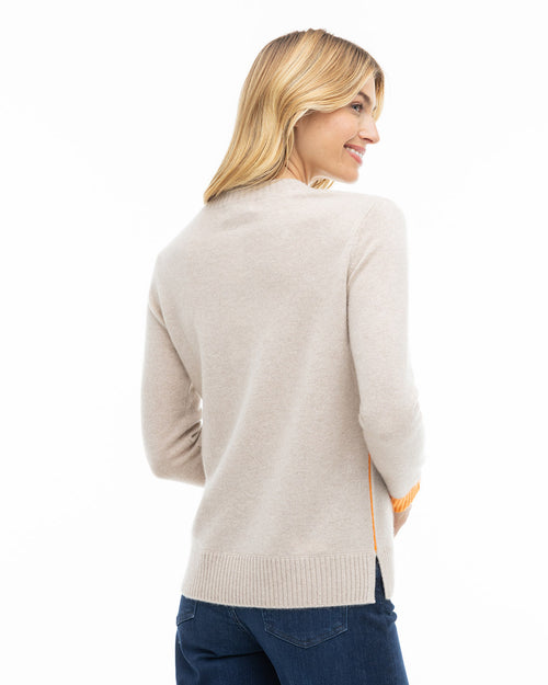 LIFESTYLE / EDITORIAL: Woman smiling, wearing beige cashmere sweater with orange detail, shown from back and side angle