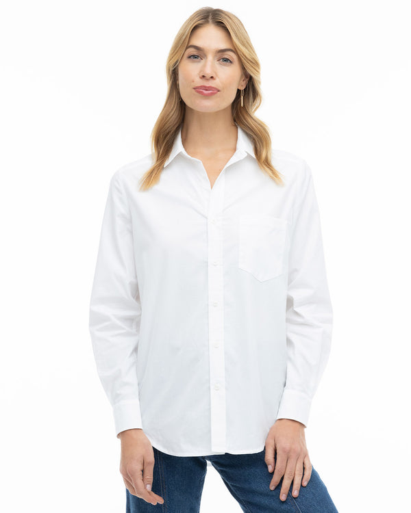 LIFESTYLE / EDITORIAL: Woman wearing a classic white button-up shirt and blue jeans, standing against a white background
