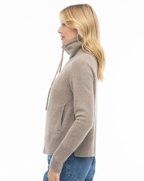 LIFESTYLE / EDITORIAL: Side profile of woman wearing driftwood-colored cashmere turtleneck sweater with drawstrings and jeans