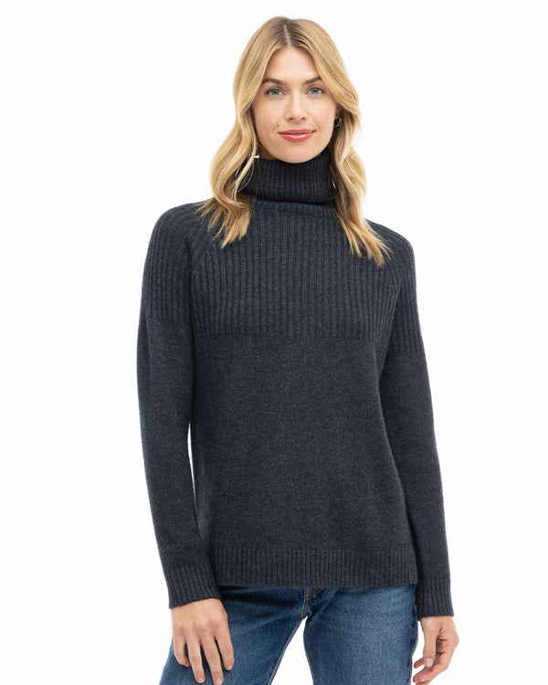 Front view image of a woman wearing charcoal cashmere turtleneck sweater with jeans, standing against white background