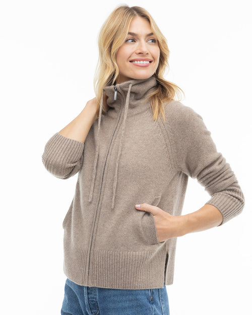 Woman wearing driftwood-colored zip-up cashmere sweater with high collar and ribbed cuffs and hem