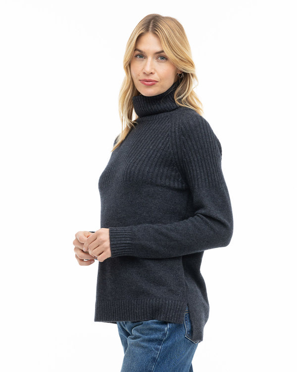 LIFESTYLE / EDITORIAL: Woman wearing charcoal turtleneck cashmere sweater and jeans, standing against white background
