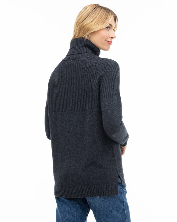 Woman wearing charcoal turtleneck cashmere sweater with ribbed upper back and side slits, viewed from behind