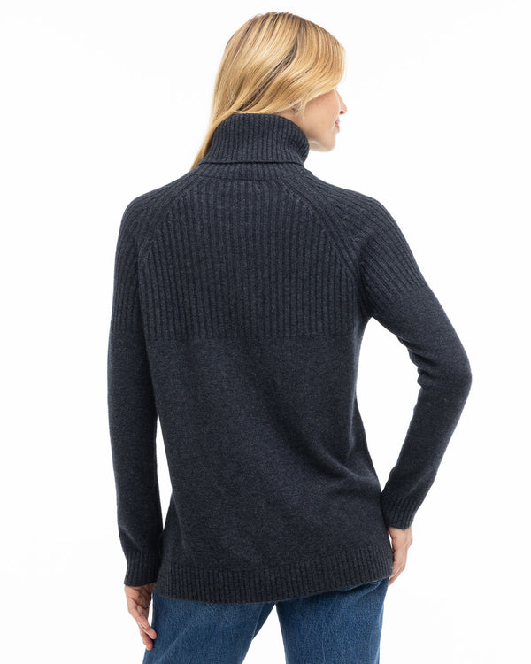 LIFESTYLE / EDITORIAL: Woman wearing charcoal turtleneck cashmere sweater, back view, paired with blue jeans