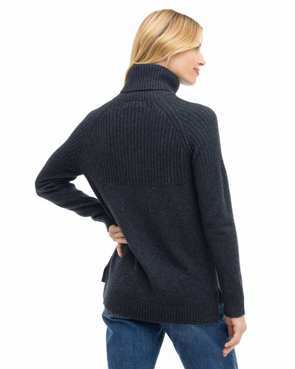 LIFESTYLE / EDITORIAL: Woman wearing charcoal ribbed turtleneck cashmere sweater, shown from back, paired with blue jeans