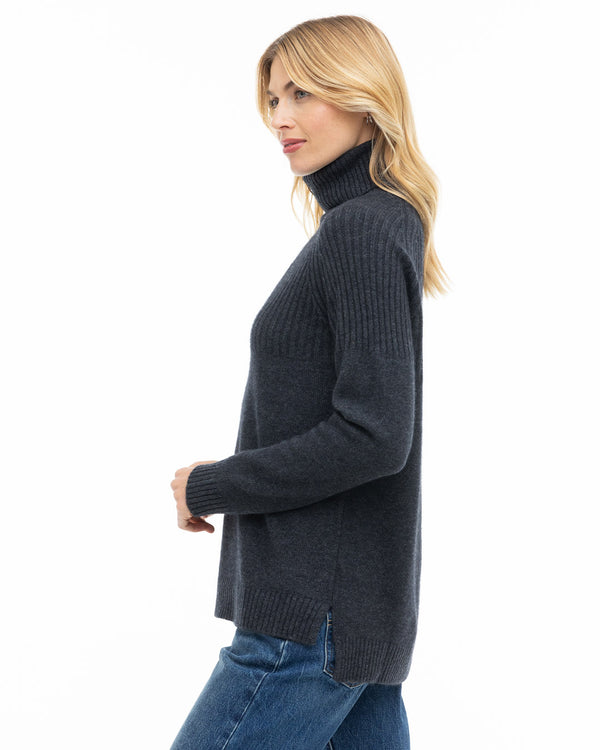 LIFESTYLE / EDITORIAL: Woman in charcoal turtleneck cashmere sweater and blue jeans, side profile on white background