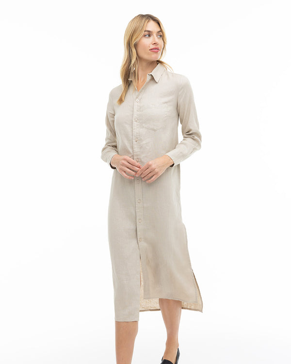 Woman wearing long sandstone button-up shirt dress with collar, standing against white background