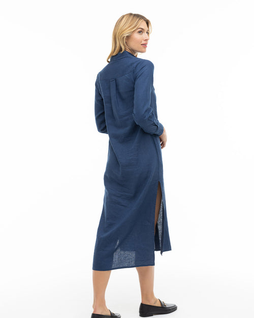 LIFESTYLE / EDITORIAL: Woman in navy long-sleeve cashmere dress with side slit, standing and looking over shoulder