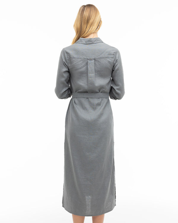 Woman wearing long graphite gray belted dress, back view, standing against white background
