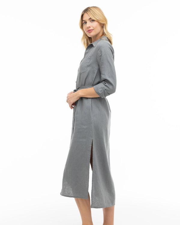 LIFESTYLE / EDITORIAL: Woman in gray long-sleeve midi dress with side slit, standing against white background