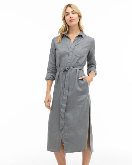 LIFESTYLE / EDITORIAL: Woman wearing a long grey belted shirt dress with rolled sleeves and side slits on white background