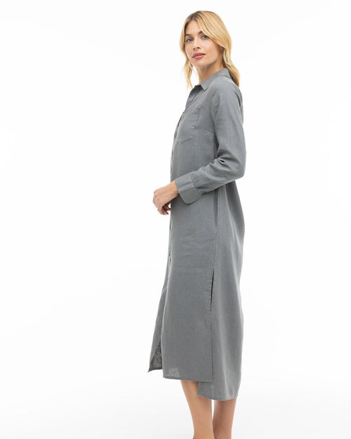 LIFESTYLE / EDITORIAL: Woman in long gray shirt dress standing sideways against white background