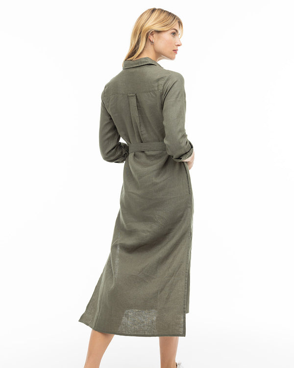 LIFESTYLE / EDITORIAL: Woman in dark olive long linen dress, back view, standing against white background