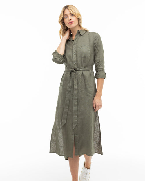 LIFESTYLE / EDITORIAL: Woman wearing dark olive shirt dress with belt and white sneakers against white background