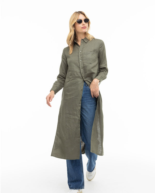 Woman wearing dark olive long buttoned shirt dress over blue jeans and white shoes, with sunglasses, on white background