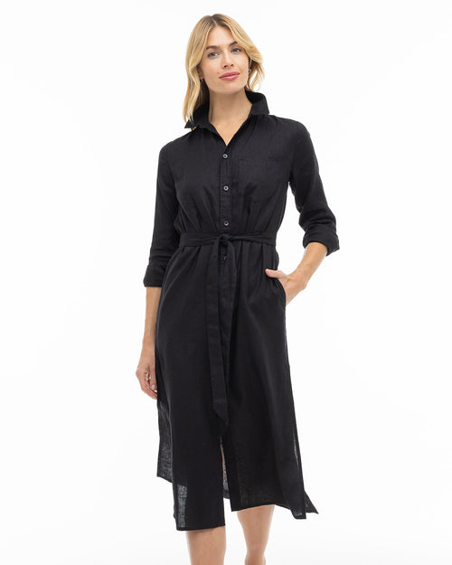 LIFESTYLE / EDITORIAL: Woman wearing a black button-up midi dress with a waist tie, standing against a white background