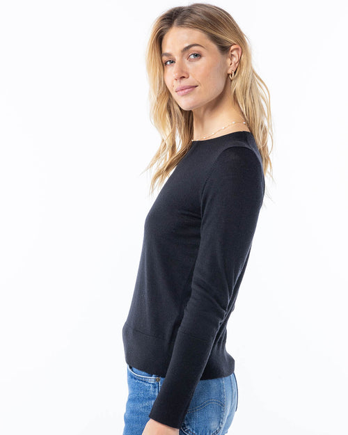LIFESTYLE / EDITORIAL: Woman in black cashmere sweater and blue jeans, side profile against white background
