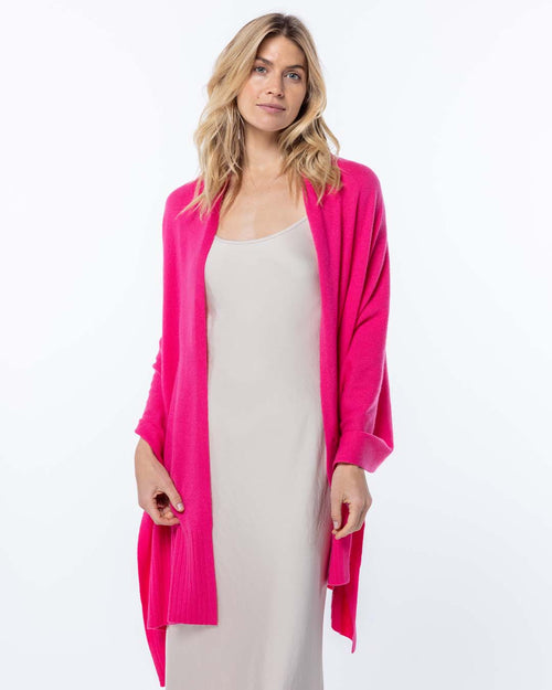 LIFESTYLE / EDITORIAL: Woman wearing bright pink cashmere cardigan over beige slip dress against white background
