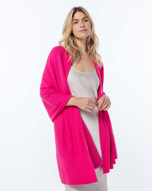 LIFESTYLE / EDITORIAL: Woman wearing bright pink cashmere cardigan over light beige slip dress against white background