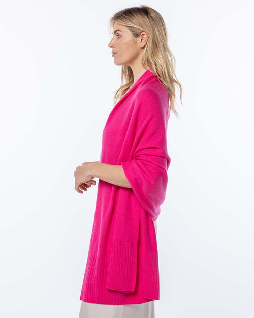 LIFESTYLE / EDITORIAL: Woman in profile wearing bright pink cashmere cardigan against white background