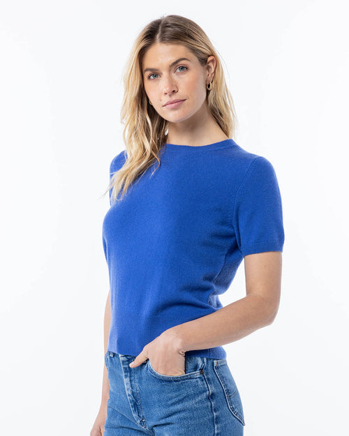 LIFESTYLE / EDITORIAL: Woman wearing a French blue short-sleeve cashmere sweater and jeans against a white background