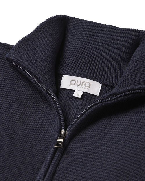 Close-up of navy blue cashmere sweater collar with zipper and "pura" brand label in size medium