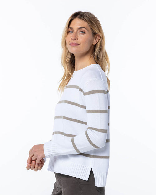 LIFESTYLE / EDITORIAL: Woman wearing white cashmere sweater with mushroom-colored horizontal stripes, side view on white