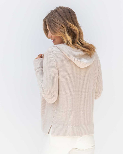 LIFESTYLE / EDITORIAL: Woman wearing oatmeal-colored ribbed cotton hoodie, viewed from back against white background