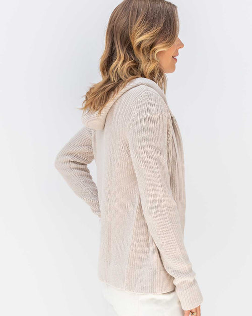 Side view of woman wearing oatmeal-colored cotton hoodie with ribbed knit texture and hood